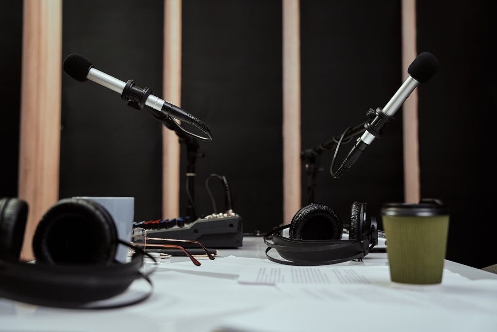 Posto di lavoro del conduttore radiofonico. Primo piano di microfoni, cuffie e mixer audio sul tavolo in uno studio di registrazione o in una sala di trasmissione. Messa a fuoco selettiva sui microfoni. Ripresa orizzontale